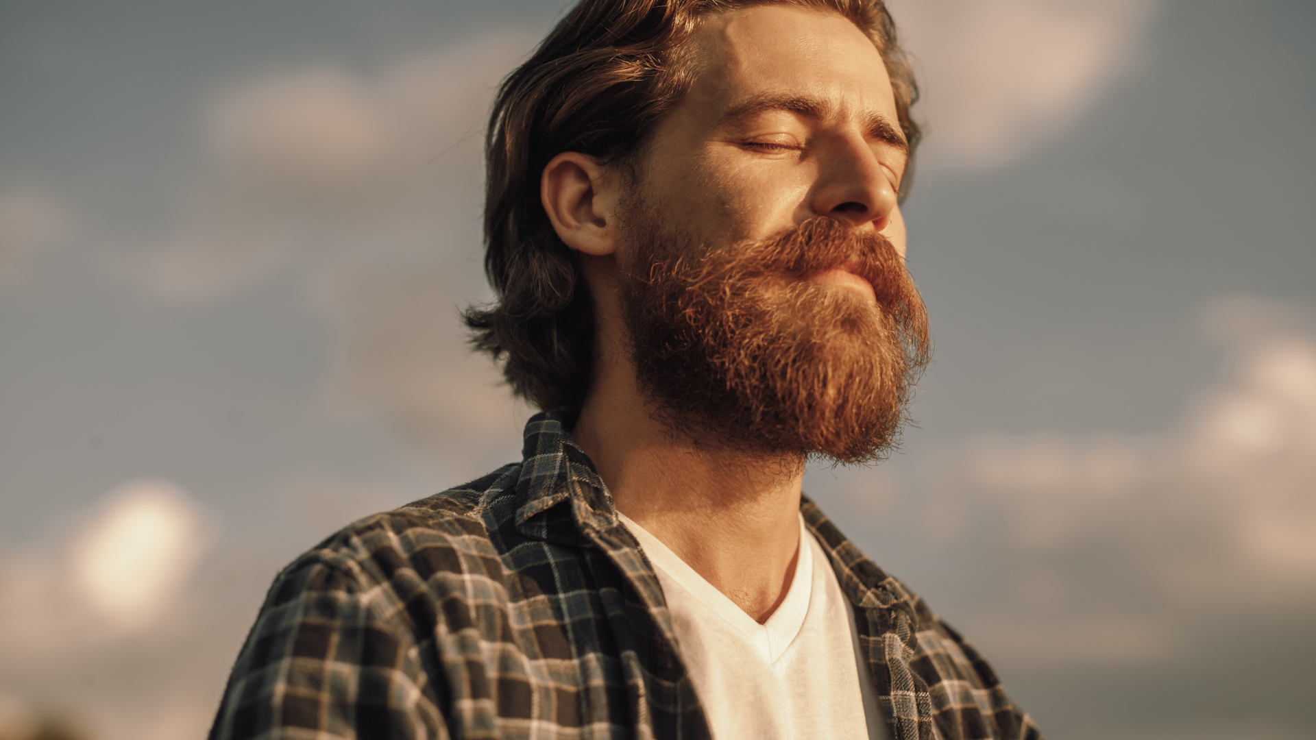 Un homme avec une barbe ferme les yeux pour ressentir le calme