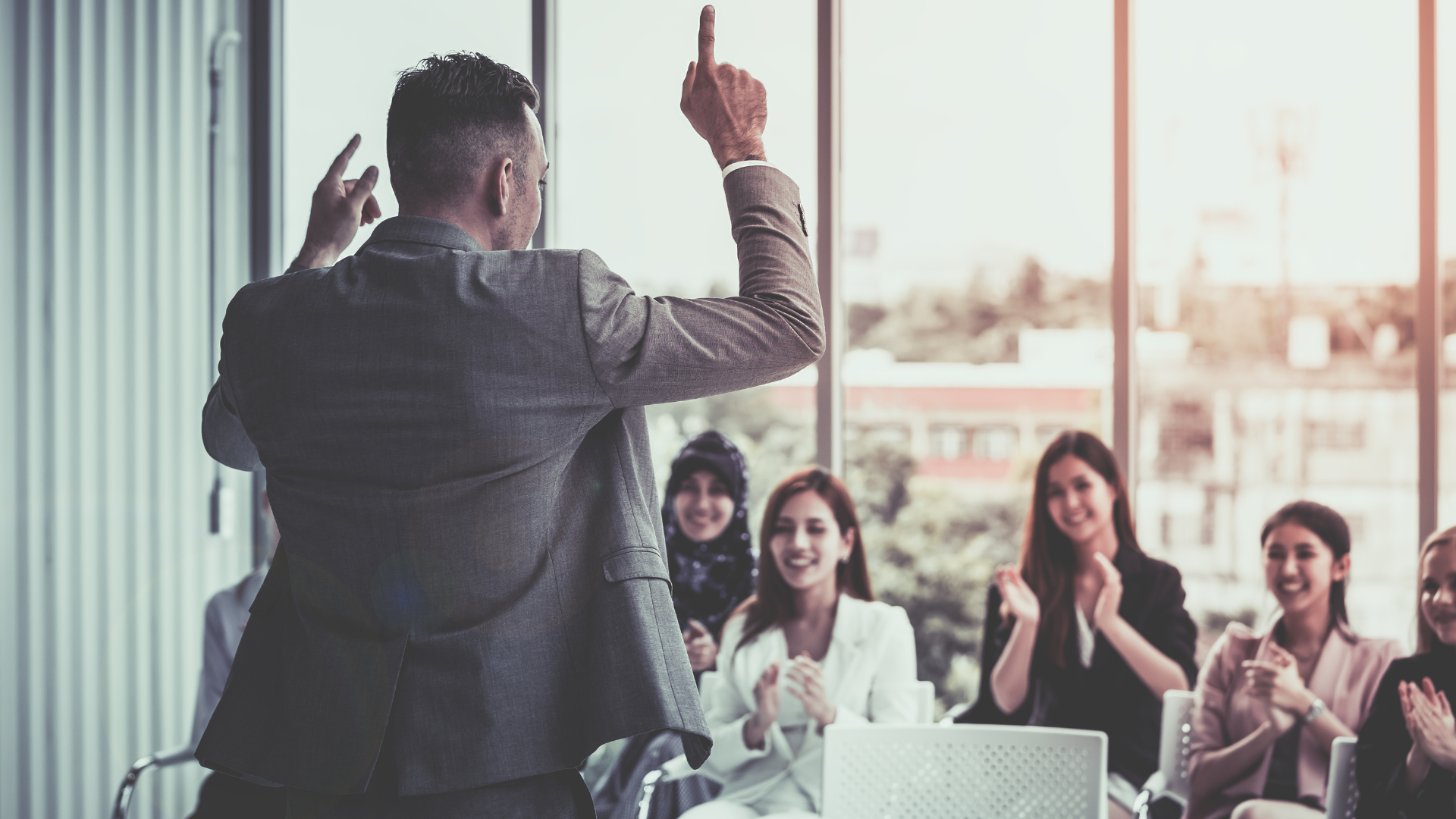 Un homme pointe le plafond en faisant un discours à une assemblée